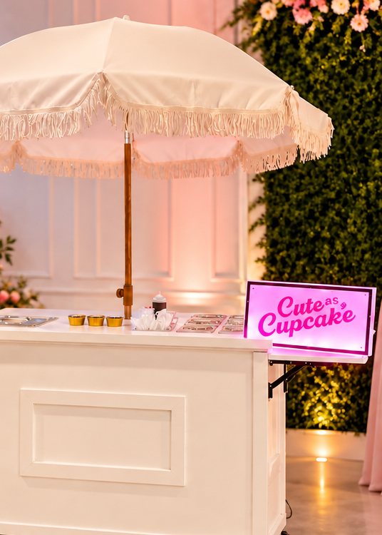 The white mobile dessert cart with a fringed umbrella and a pink Cute as a Cupcake sign