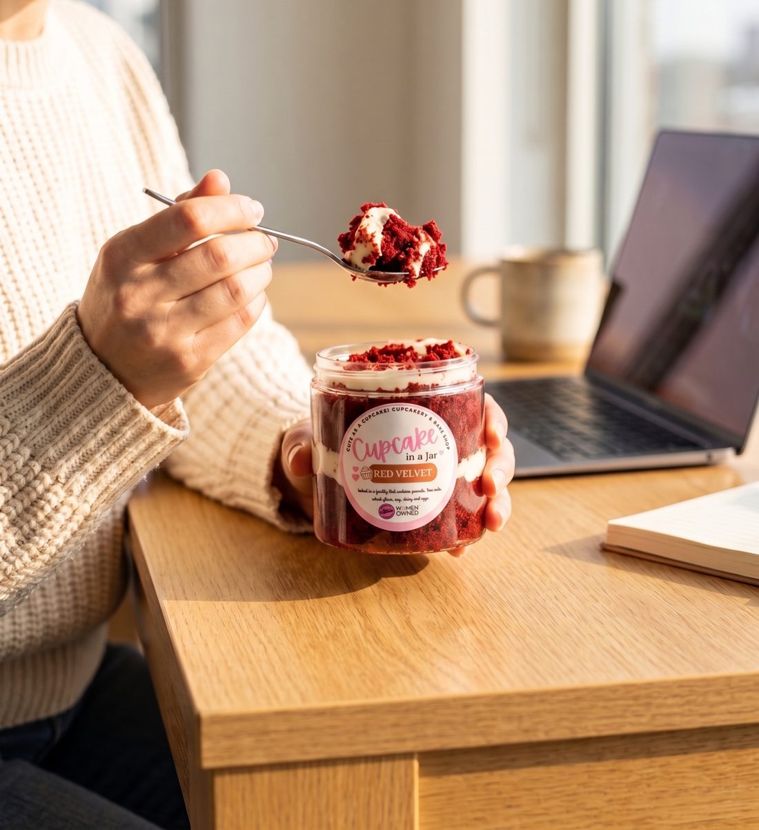 Someone at a desk eating a Red Velvet Cupcake in a Jar