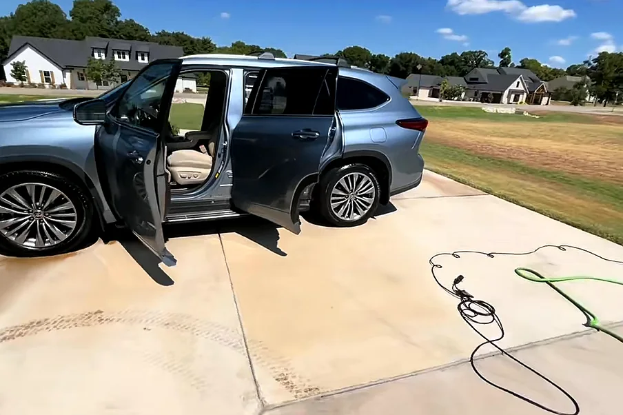 A silver Toyota Highlander with every door open on a driveway, mid-detail