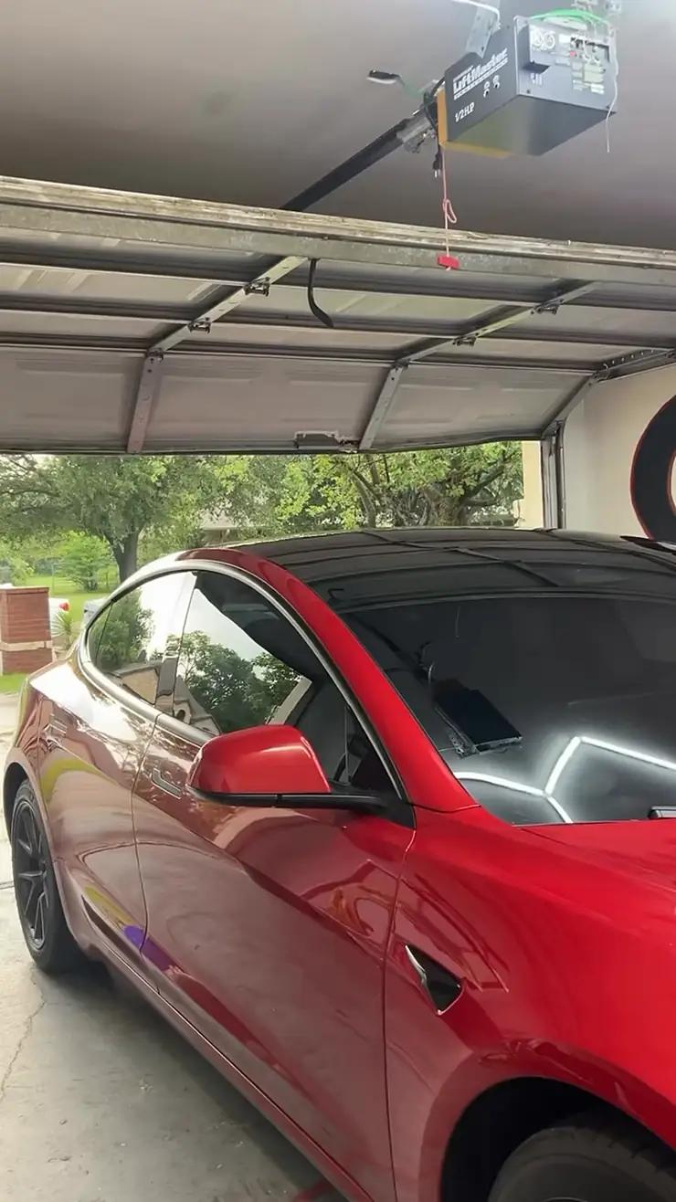 A red Tesla in the GTZ Tint bay under a hexagon light grid