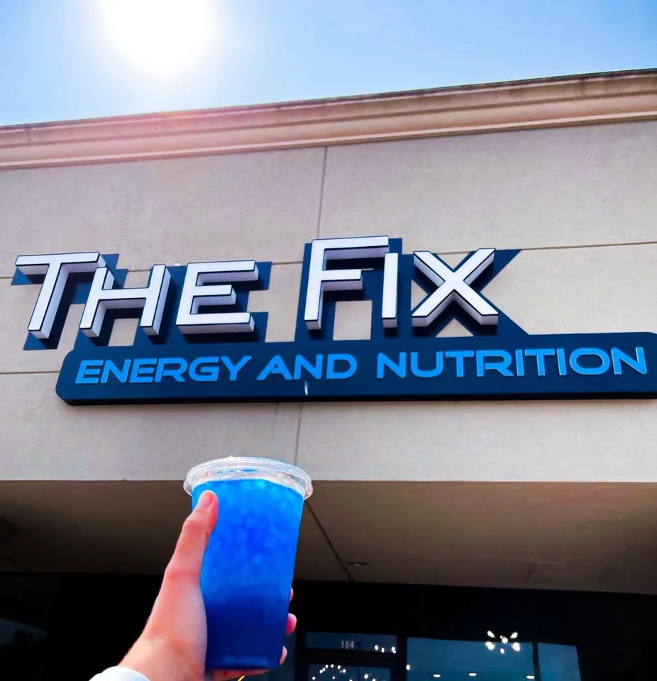 A blue tea held up under THE FIX sign on a sunny day
