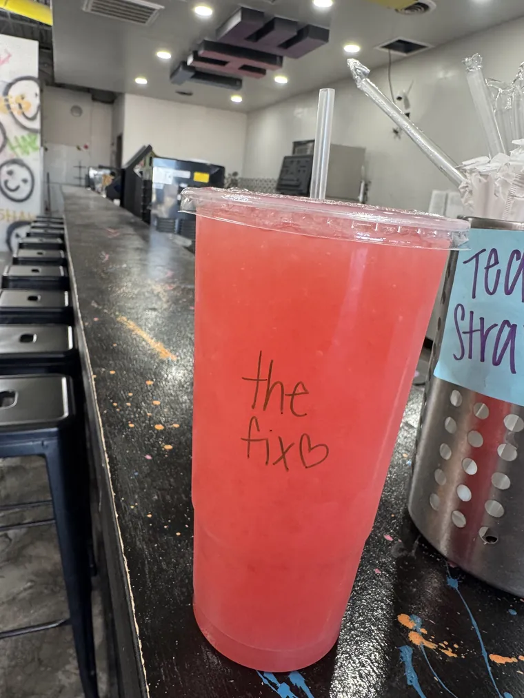 A pink tea on the counter with the fix written on the cup