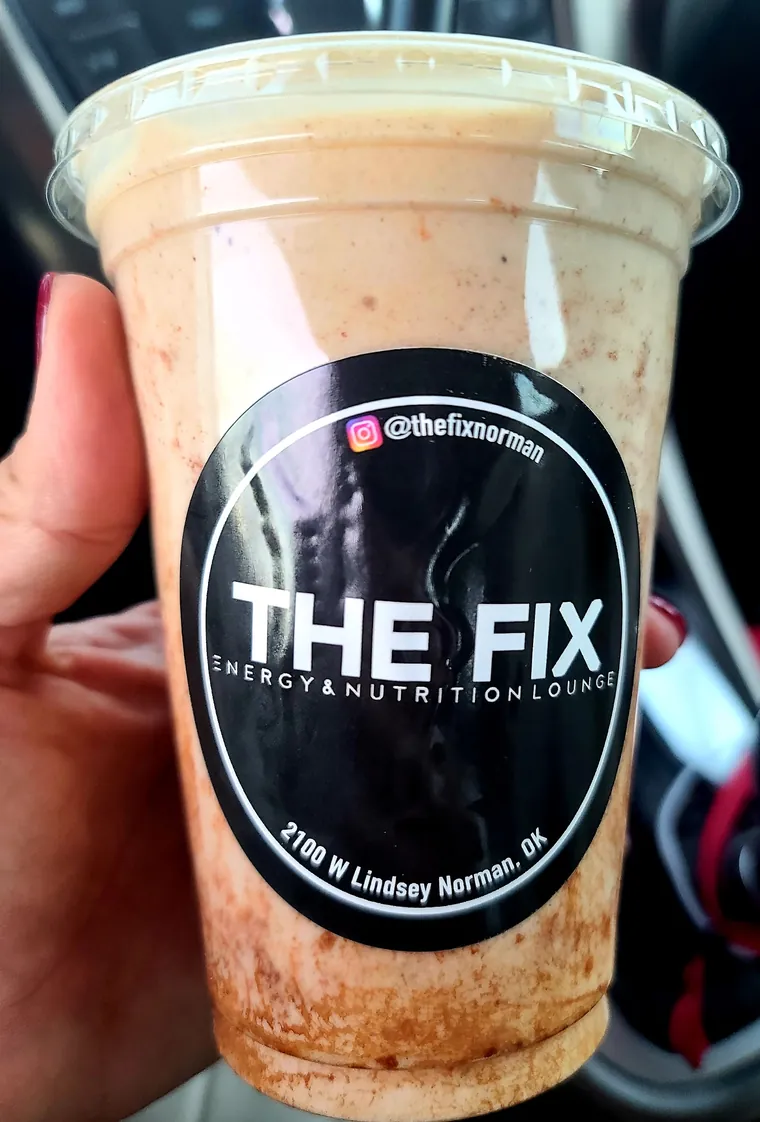 A cinnamon protein shake in a cup with The Fix sticker