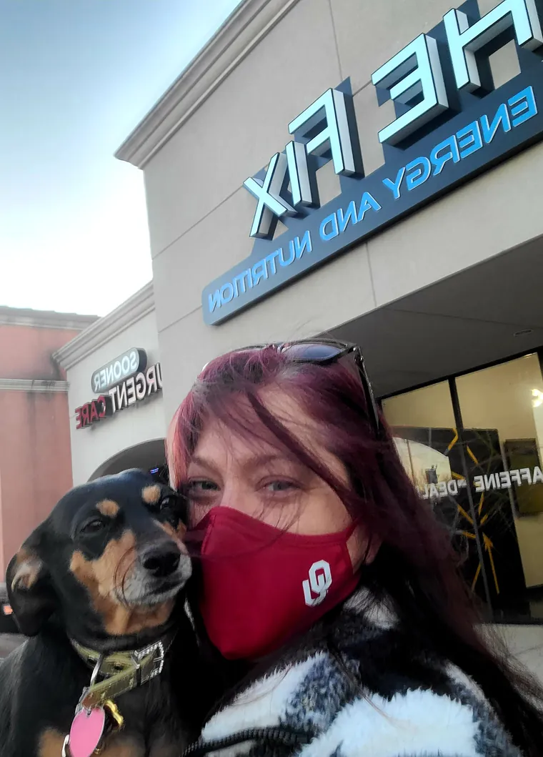 A regular and her dog outside under the storefront sign