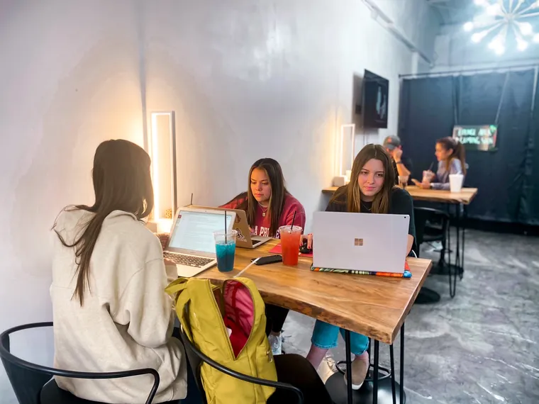 Students working at the long wooden table inside The Fix