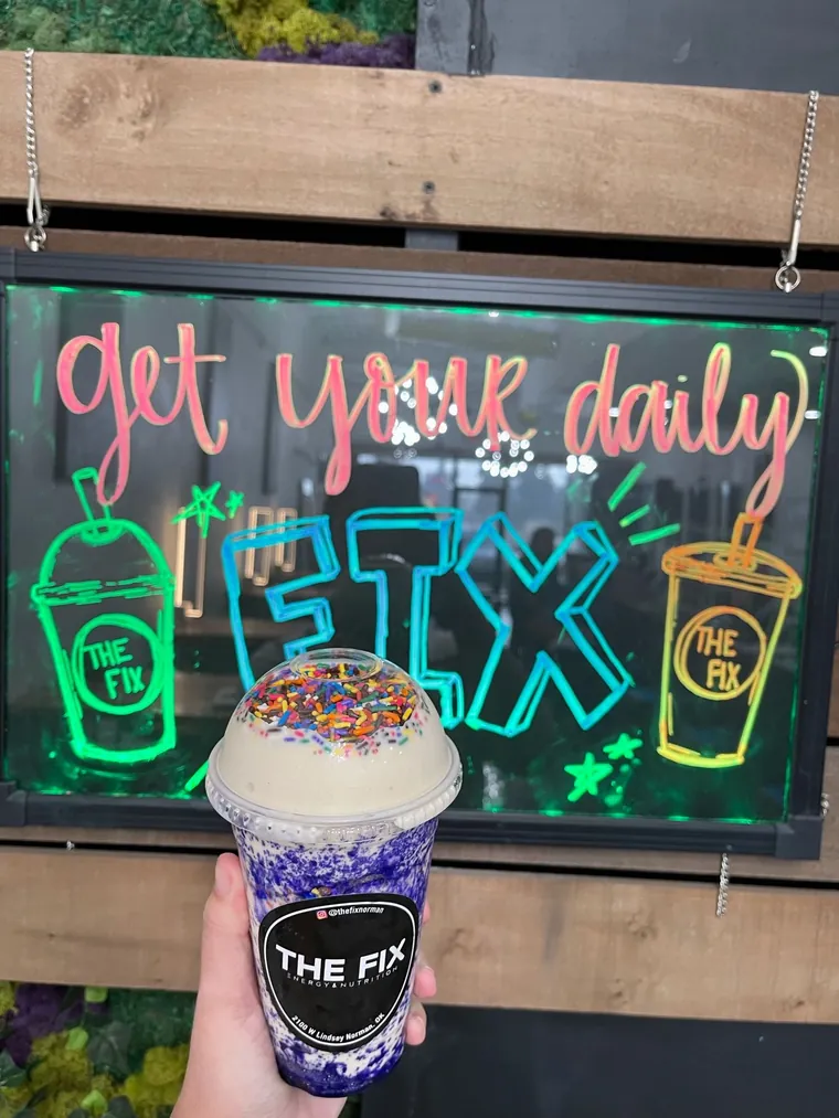 A sprinkled shake in front of the get your daily FIX neon sign