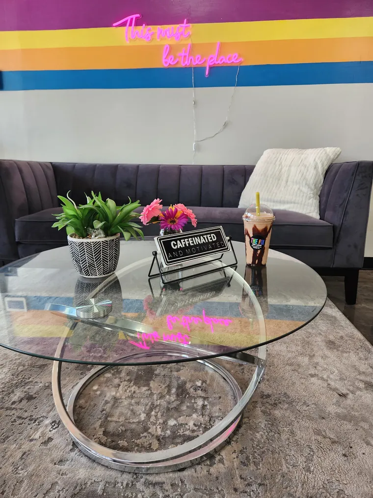 The lounge corner: couch, glass table and the striped mural
